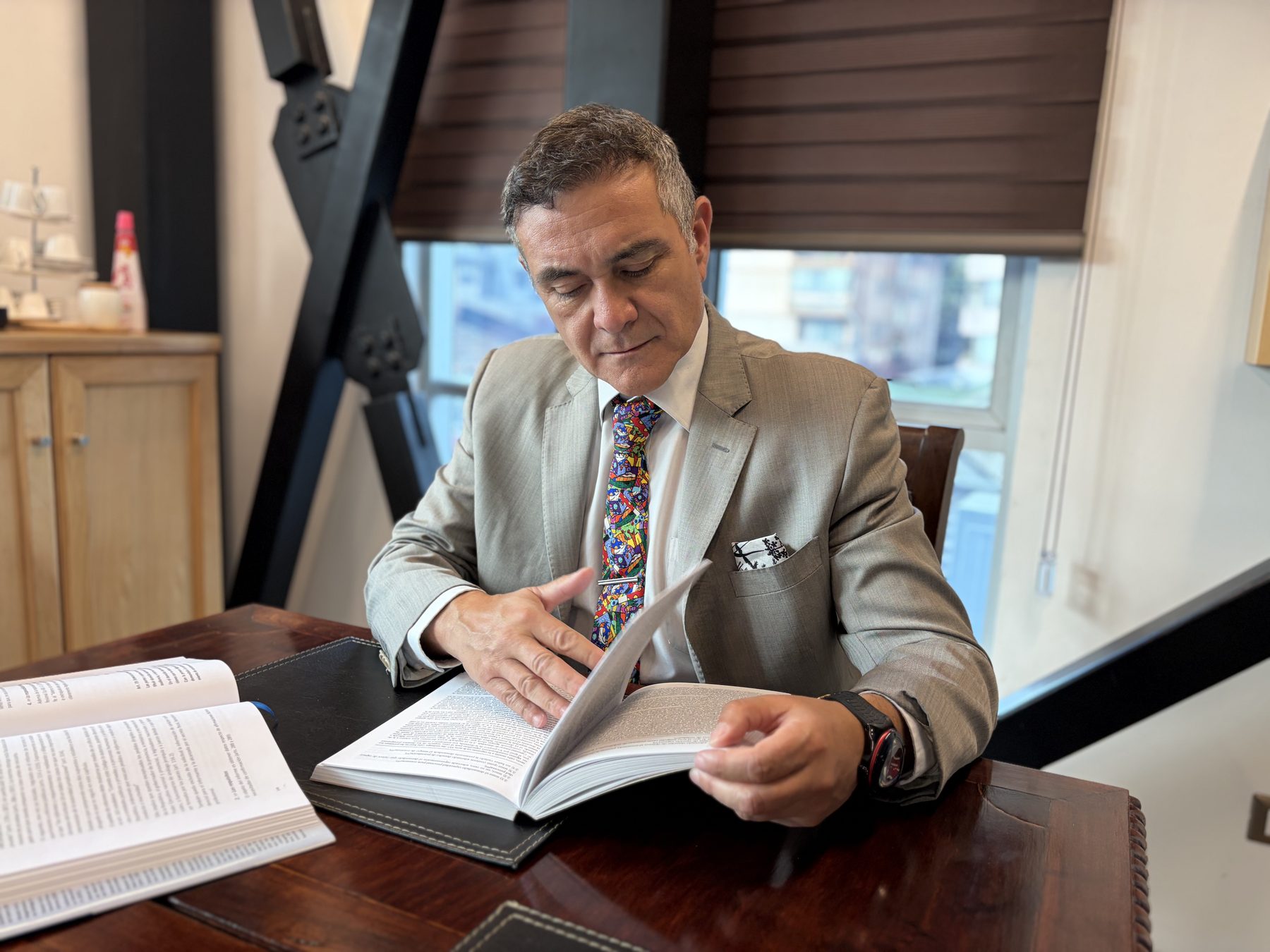 Remberto Valdés revisando un libro en su escritorio